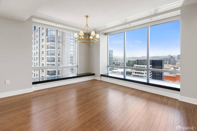 spare room featuring crown molding, a notable chandelier, and hardwood / wood-style flooring