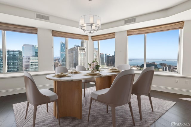 dining space with a chandelier, dark hardwood / wood-style flooring, and a water view