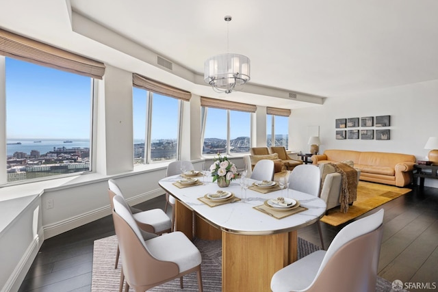 dining room featuring an inviting chandelier, dark hardwood / wood-style floors, and a water view