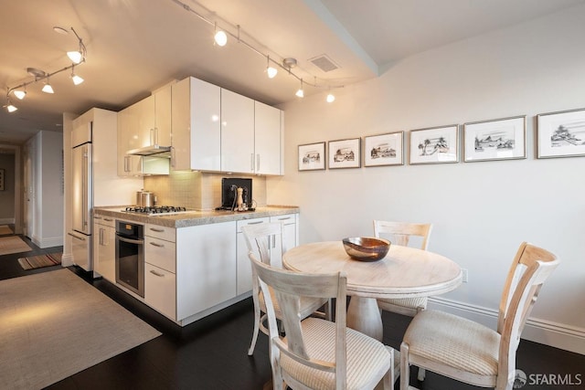 kitchen with white cabinets, appliances with stainless steel finishes, tasteful backsplash, and rail lighting