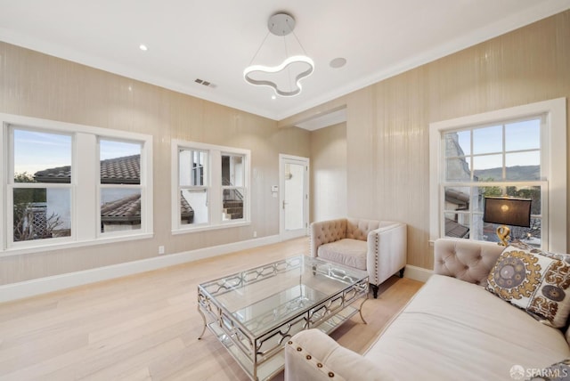 living room featuring a chandelier, light wood-style flooring, baseboards, and ornamental molding