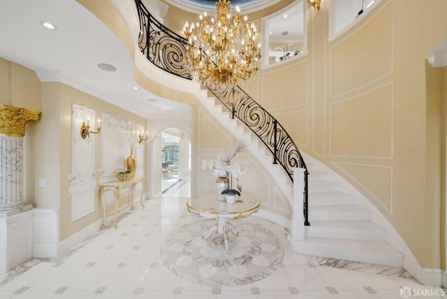 stairs with arched walkways, ornamental molding, a high ceiling, a chandelier, and inlaid floor details
