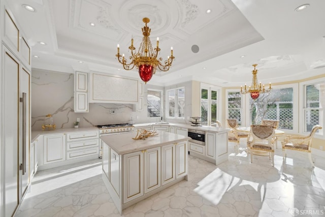 kitchen with a chandelier, a tray ceiling, recessed lighting, light countertops, and a center island