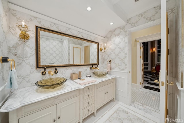 bathroom with a wainscoted wall, double vanity, recessed lighting, and wallpapered walls