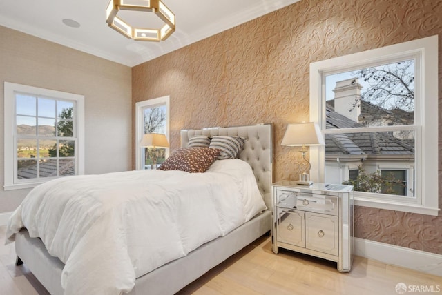 bedroom featuring light wood finished floors, baseboards, wallpapered walls, and ornamental molding