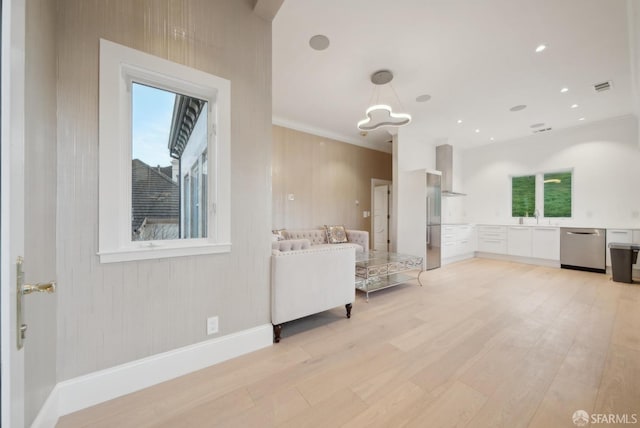 living room featuring ornamental molding, light wood finished floors, healthy amount of natural light, a chandelier, and baseboards