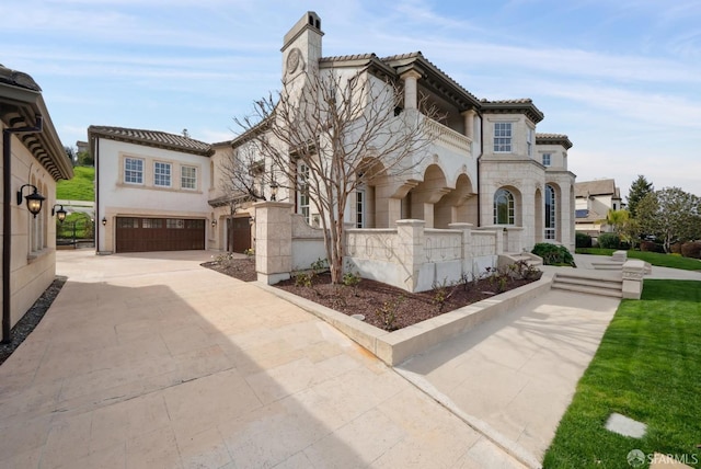 mediterranean / spanish home featuring a garage, a chimney, a tile roof, and stucco siding
