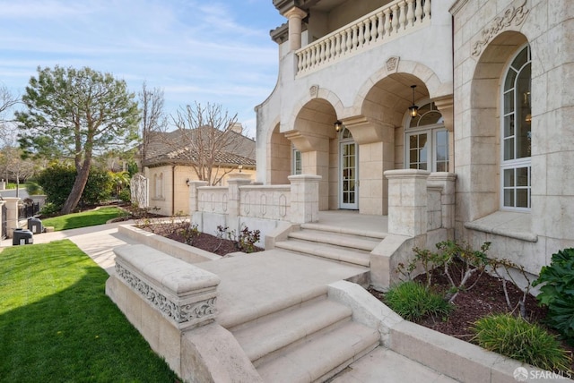 entrance to property with stone siding, a lawn, and a balcony