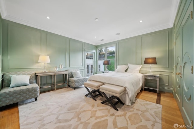 bedroom featuring a decorative wall, ornamental molding, light wood-type flooring, and recessed lighting