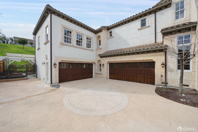 view of front of house with a garage, curved driveway, stucco siding, fence, and a tiled roof