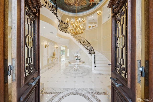 entryway featuring ornamental molding, a chandelier, arched walkways, stairs, and baseboards