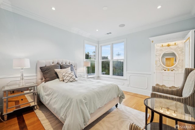 bedroom featuring wood finished floors, wainscoting, ornamental molding, recessed lighting, and connected bathroom
