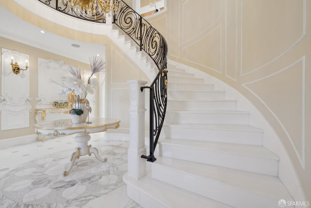stairs with a towering ceiling, ornamental molding, and a chandelier