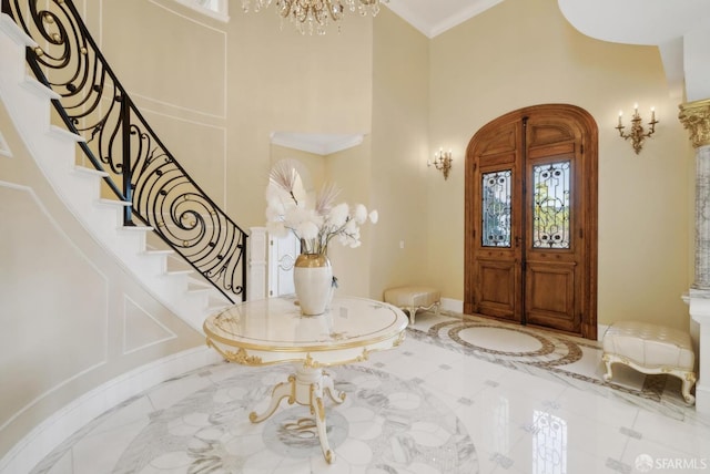 entrance foyer featuring a towering ceiling, inlaid floor details, stairway, a chandelier, and baseboards