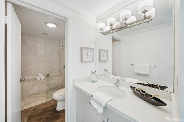 bathroom with vanity, ornamental molding, a tile shower, and toilet