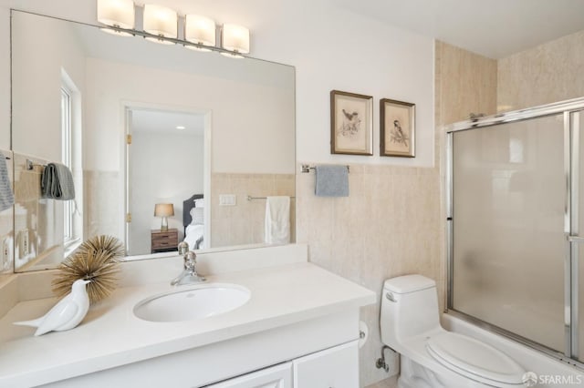 bathroom featuring toilet, vanity, and tile walls