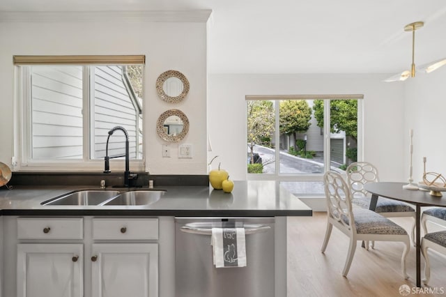 kitchen with a sink, dark countertops, ornamental molding, and dishwasher