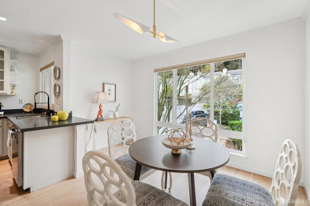 dining room featuring baseboards, crown molding, and light wood finished floors