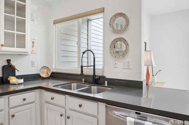 kitchen with dark countertops, dishwasher, white cabinetry, and a sink