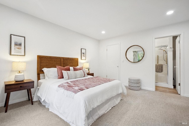 bedroom with ensuite bathroom and light colored carpet