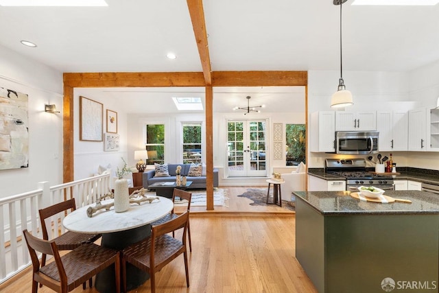 kitchen featuring appliances with stainless steel finishes, a skylight, beamed ceiling, white cabinets, and decorative light fixtures