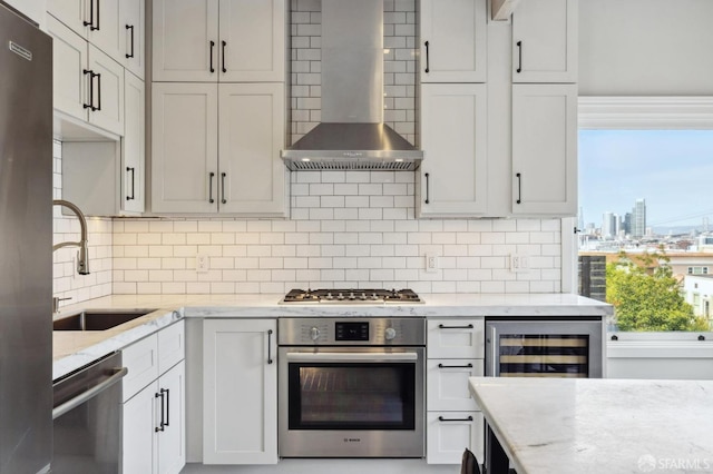 kitchen with light stone countertops, wall chimney range hood, stainless steel appliances, and wine cooler