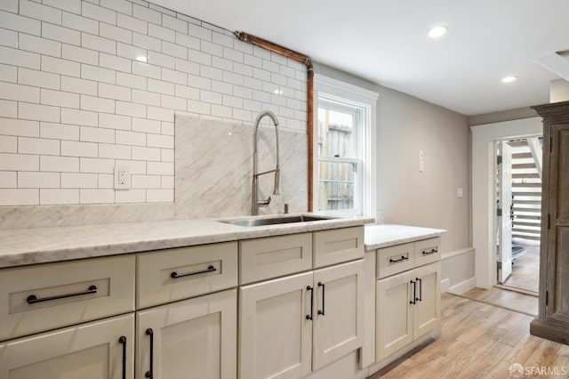 kitchen with light hardwood / wood-style flooring, light stone countertops, and sink