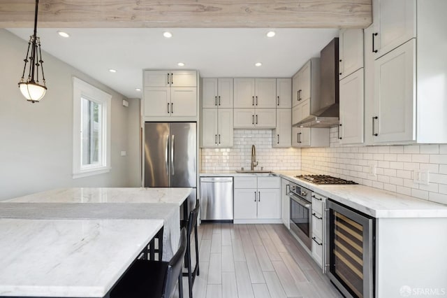 kitchen with pendant lighting, wine cooler, sink, wall chimney range hood, and stainless steel appliances