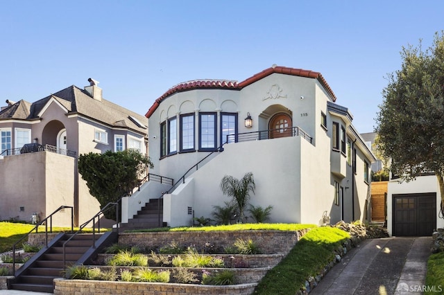 mediterranean / spanish house featuring a garage, stucco siding, driveway, and stairs