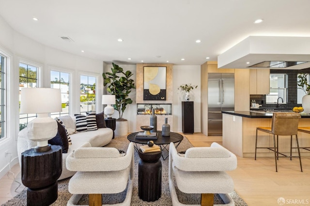 living room with a large fireplace, light wood-style flooring, visible vents, and recessed lighting