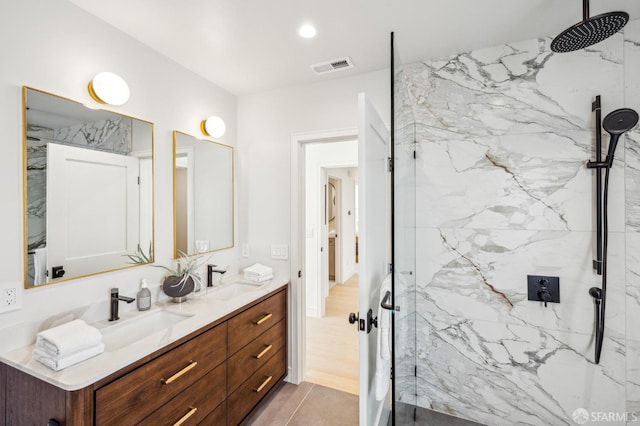 full bath with a marble finish shower, visible vents, and a sink