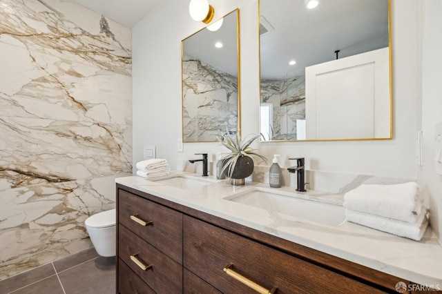 bathroom with double vanity, stone wall, a marble finish shower, and a sink