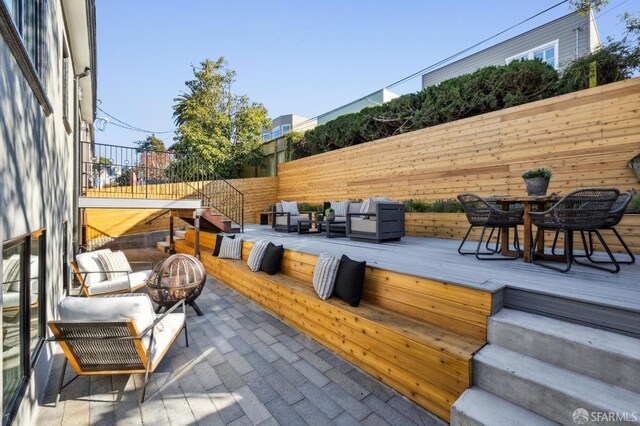 deck with outdoor dining area, a fenced backyard, and an outdoor living space