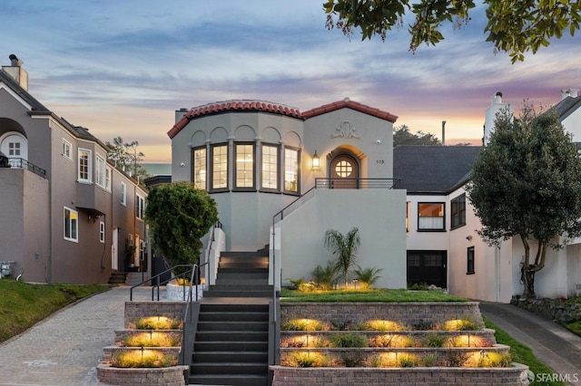 mediterranean / spanish-style home with a tile roof, stairway, and stucco siding