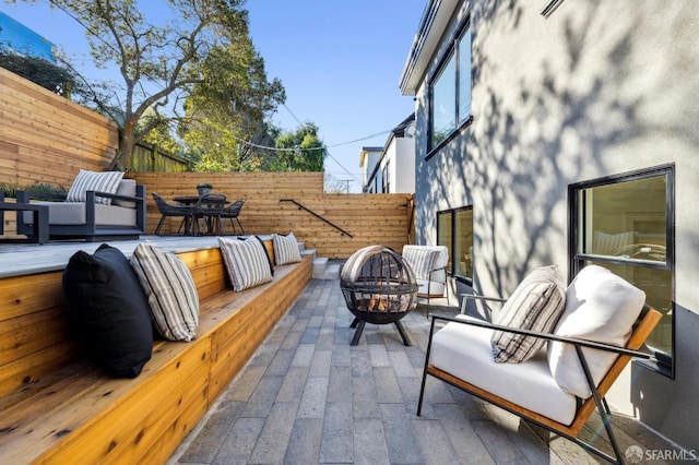 view of patio / terrace with an outdoor living space with a fire pit and fence