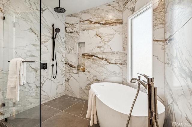 bathroom featuring stone wall, a marble finish shower, tile walls, and a soaking tub