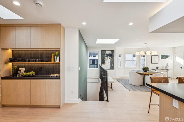 kitchen with a skylight, tasteful backsplash, light brown cabinets, and open floor plan