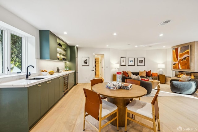 dining space with recessed lighting, visible vents, a glass covered fireplace, and light wood-style flooring