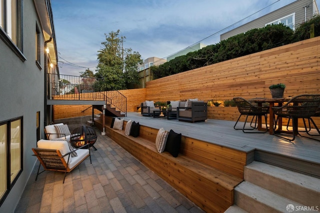 wooden terrace with outdoor dining space, a fenced backyard, and an outdoor living space with a fire pit