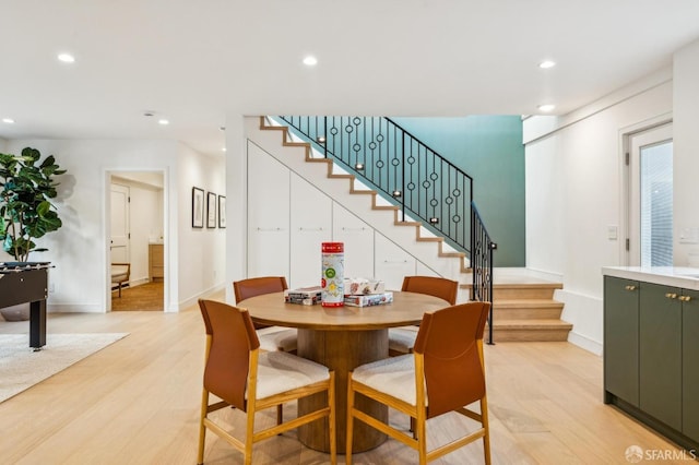 dining room featuring light wood-style floors, recessed lighting, baseboards, and stairs