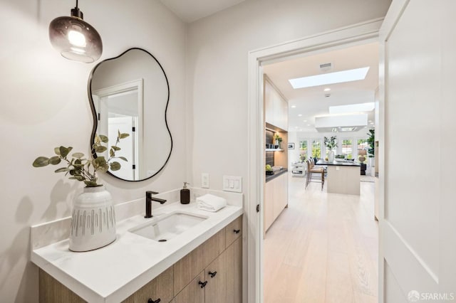 bathroom featuring visible vents, a skylight, wood finished floors, and vanity