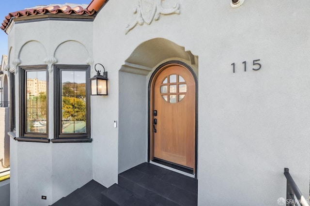 view of exterior entry featuring a tile roof and stucco siding