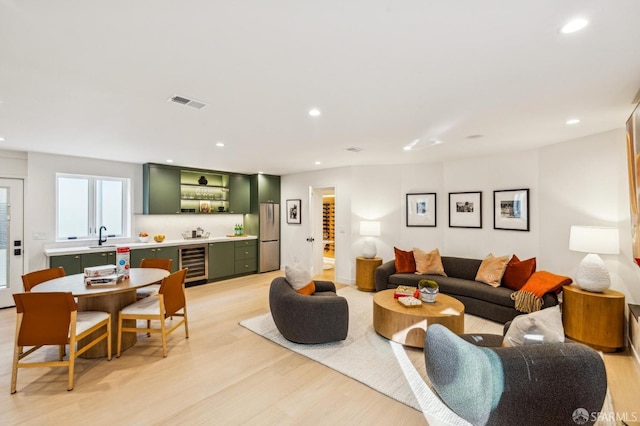 living room with light wood-type flooring, beverage cooler, indoor wet bar, and recessed lighting