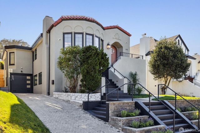 mediterranean / spanish house featuring driveway, a tile roof, stairway, and stucco siding