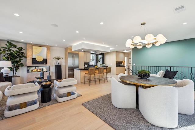 dining space featuring light wood-style floors, recessed lighting, and an inviting chandelier