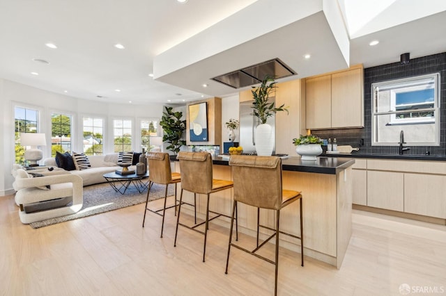 kitchen featuring a breakfast bar, dark countertops, decorative backsplash, a kitchen island, and a sink