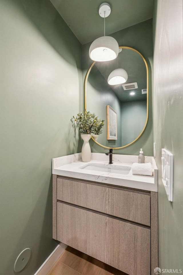 bathroom featuring visible vents, wood finished floors, vanity, and baseboards