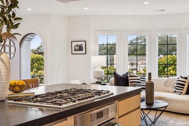 kitchen with stainless steel gas cooktop, open floor plan, oven, and a healthy amount of sunlight