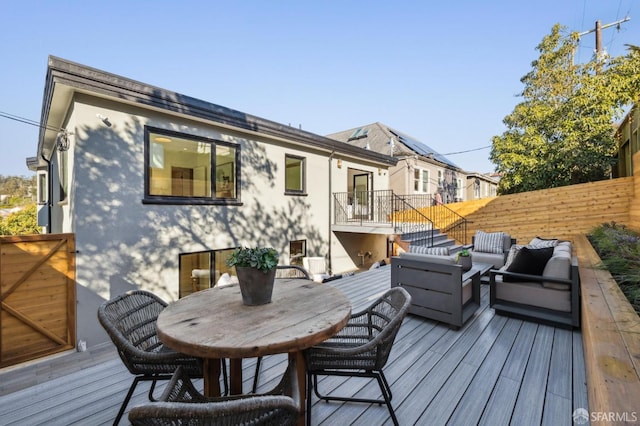 deck with outdoor dining space, fence, and an outdoor living space