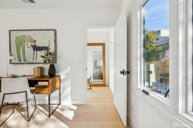 office area featuring light wood-type flooring, plenty of natural light, visible vents, and baseboards